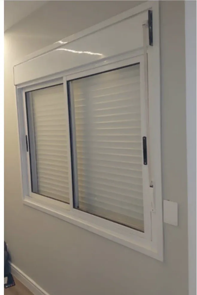 Janela de correr de alumínio branco com persiana integrada, instalada em ambiente residencial