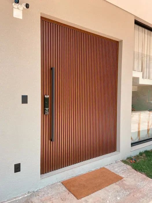Porta pivotante ripada em madeira, com fechadura eletrônica e puxador vertical, entrada de residência